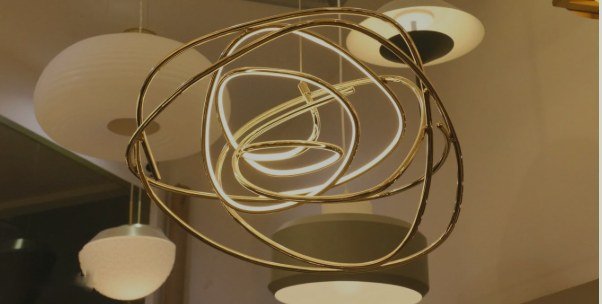 Pendente dourado de LED em aros entrelaçados, com outros pendentes ao fundo