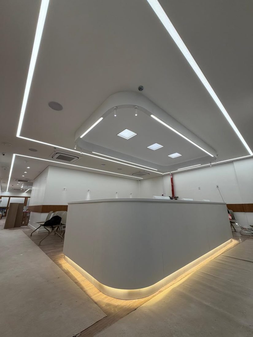 Recepção de clínica com perfis de LED no forro e fita de LED sob o balcão